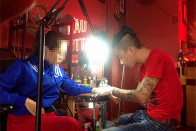 Một tay nghệ sĩ xăm đang trao đổi với khách hàng về bản thiết kế và chi phí cho hình xăm vai nữ