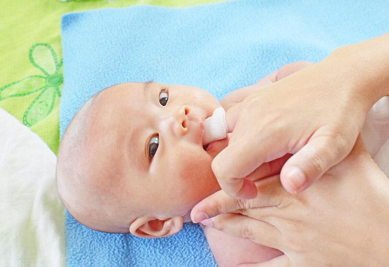 Người mẹ đang hướng dẫn cách rơ lưỡi cho bé bằng gạc Đông Pha